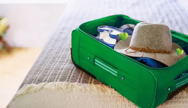 Green suitcase on a bed